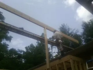 Carpenter setting a ridge beam over a new addition frame — Ice Dam Removal by Roofing Brothers in Gilmer