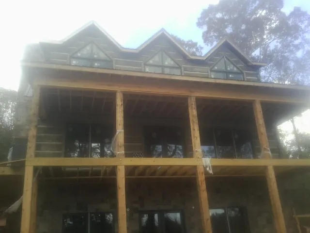 Dormers and porch framing on a large log home under construction — Roof Coating work by our crew in Gilmer