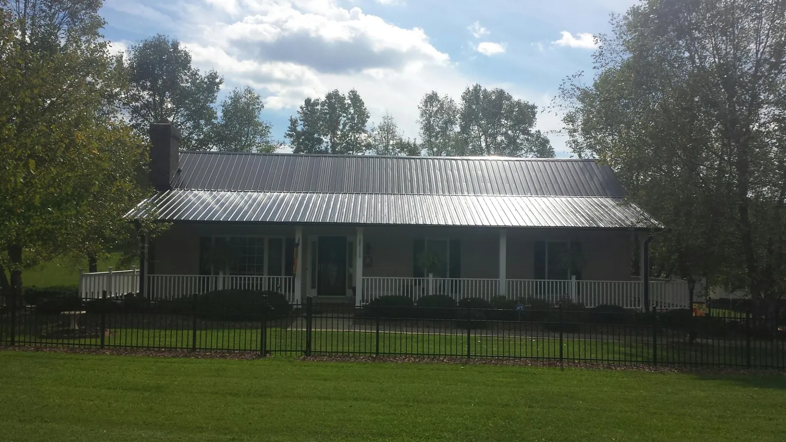 Gray metal roof on a brick ranch with a full width front porch — Gutter Guard Installation work by our crew in Gilmer
